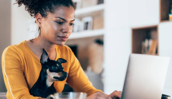 Mulher a utilizar um portátil com um cão ao colo