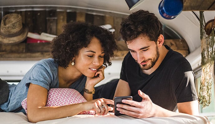 homem a comer uma refeição e a olhar para o telemóvel que inicia o Norton 360 Standard.